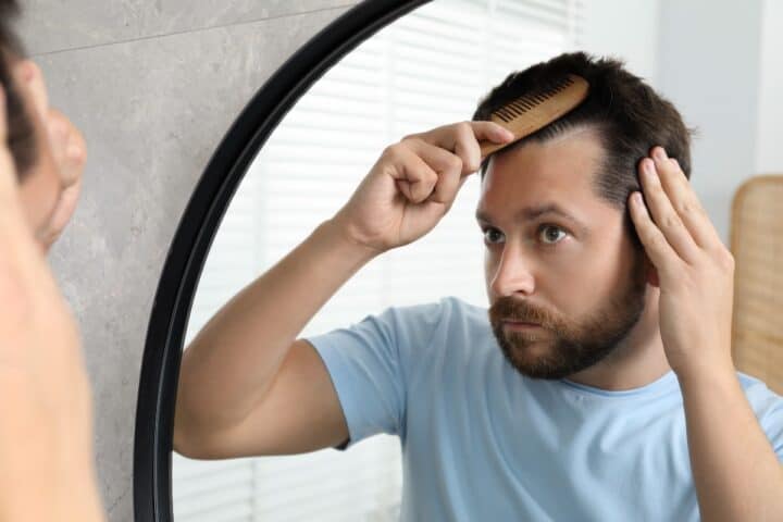 Man examining his hairline in a mirror