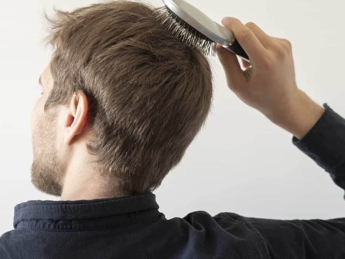 a male young adult combing his hair after taking a bath