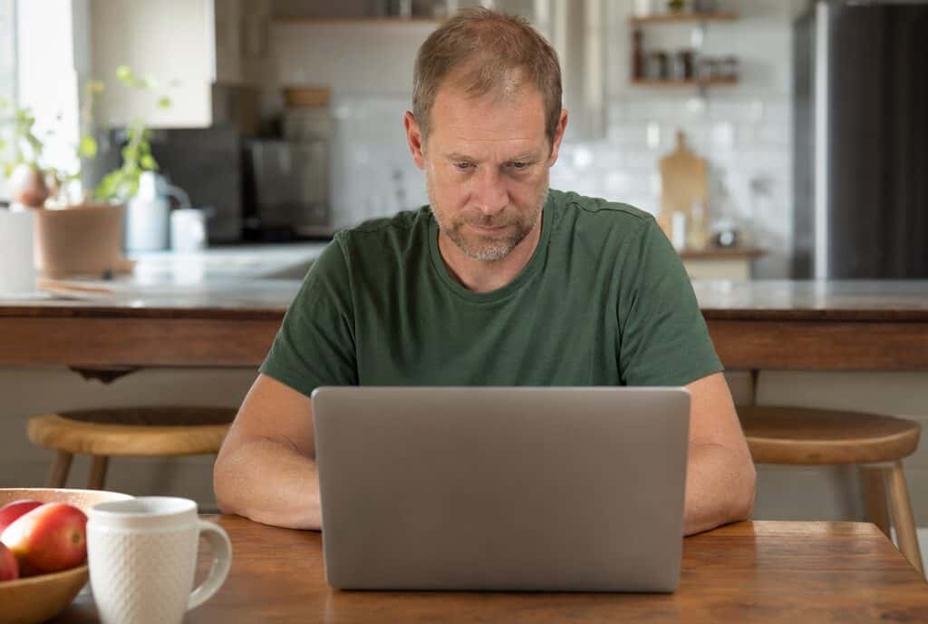 Man using a laptop at a kitchen table