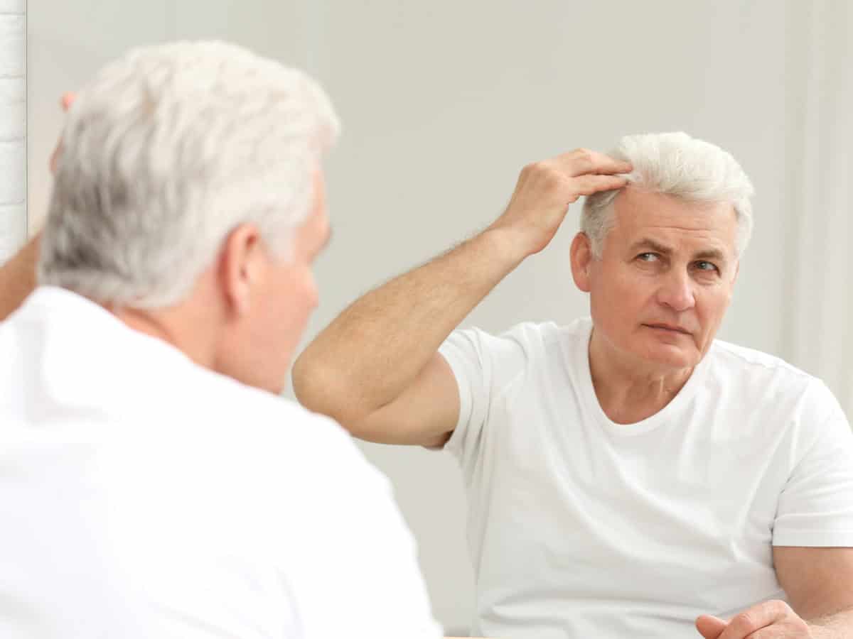 man checking hair in mirror in bright bathroom 2026 03 17 22 08 55 utc