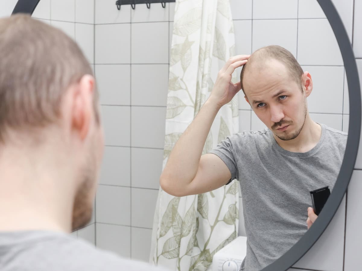 man checking hairline in bathroom mirror reflectio 2026 03 10 00 55 30 utc