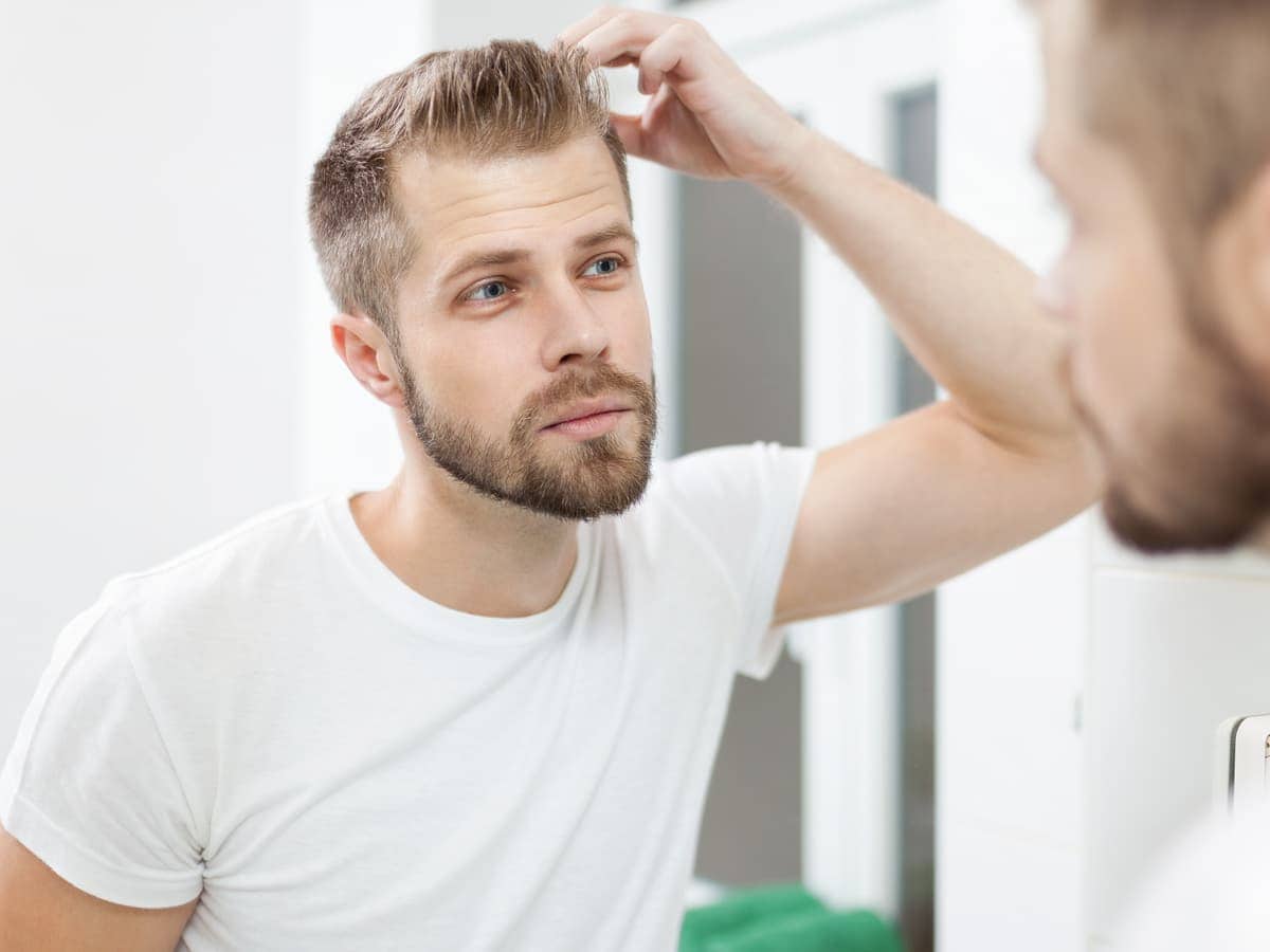 man checks hairline in bright bathroom mirror 2026 03 09 06 35 48 utc (1)