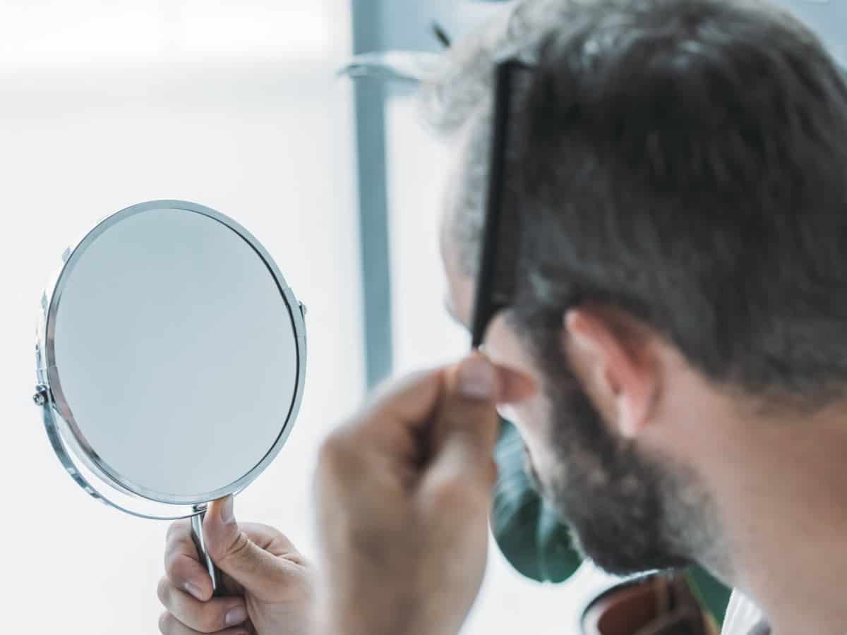 man combing his hair in front of mirror 2026 03 12 23 55 47 utc