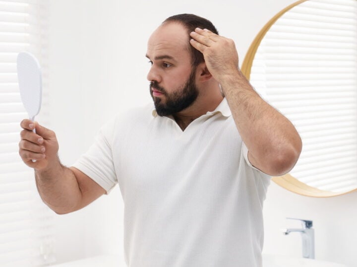man examining hair in mirror in bright bathroom 2026 03 26 23 36 47 utc