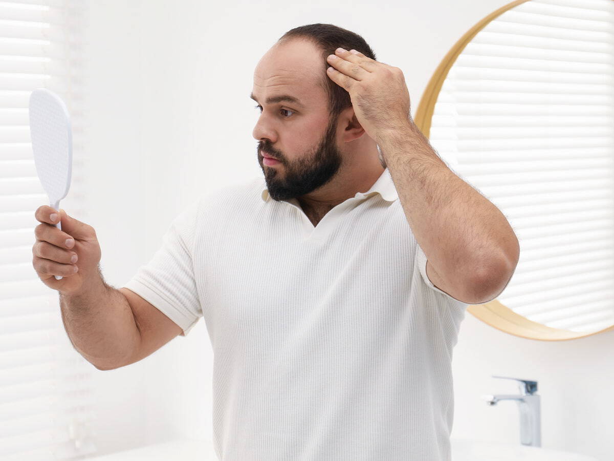 man examining hair in mirror in bright bathroom 2026 03 26 23 36 47 utc