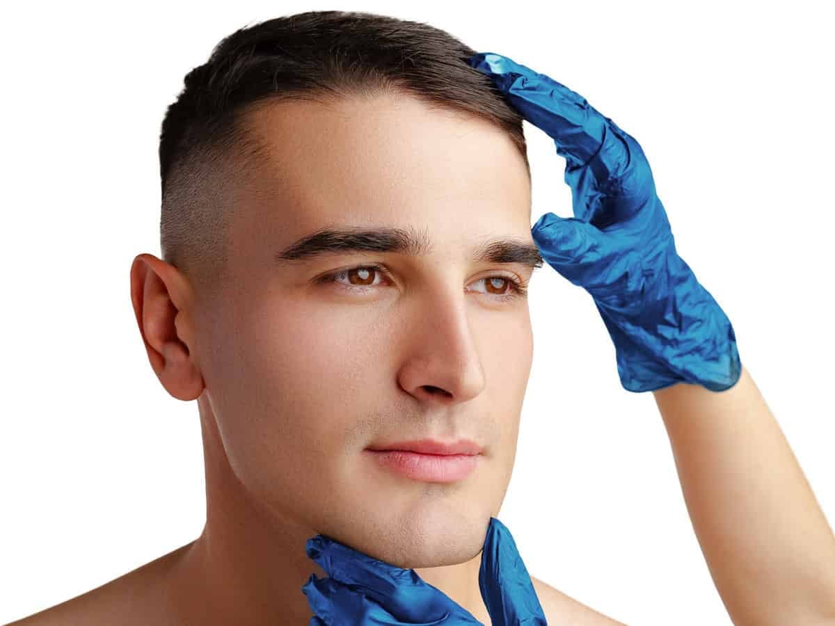 cosmetician hands in protective gloves touching face of young handsome man