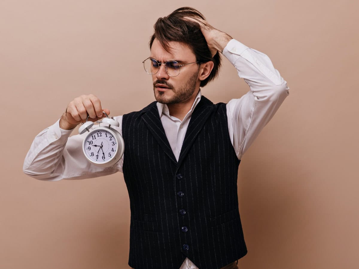 man holding clock with worried expression indoors 2026 03 09 07 09 16 utc
