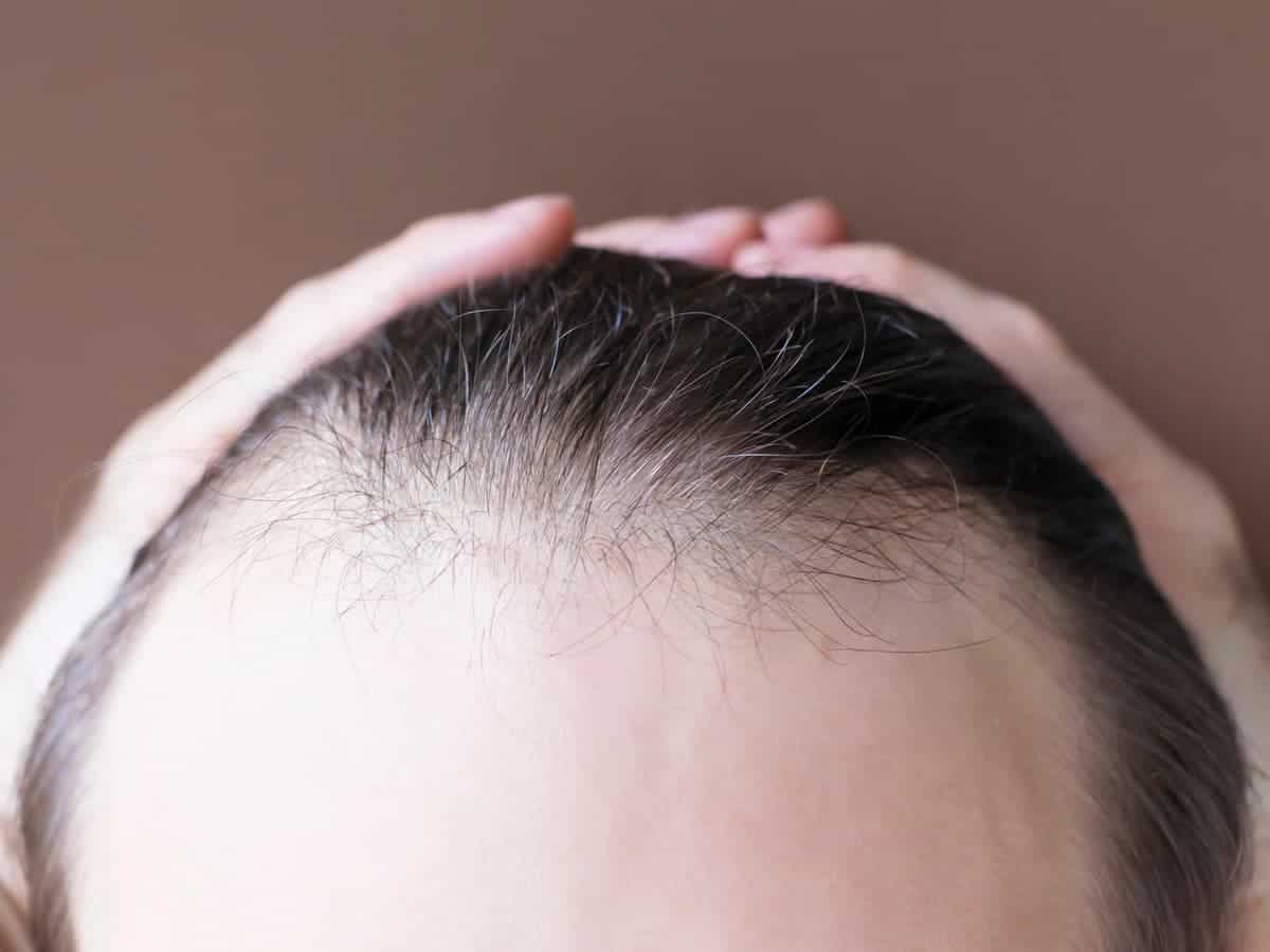 man touching her hair close up on brown background 2026 03 17 06 53 02 utc (1)