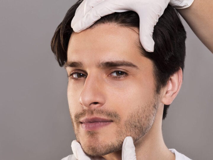 plastic surgeon examining male patient face, empty space