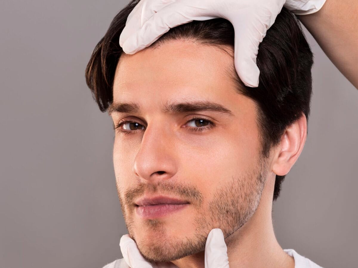 plastic surgeon examining male patient face, empty space