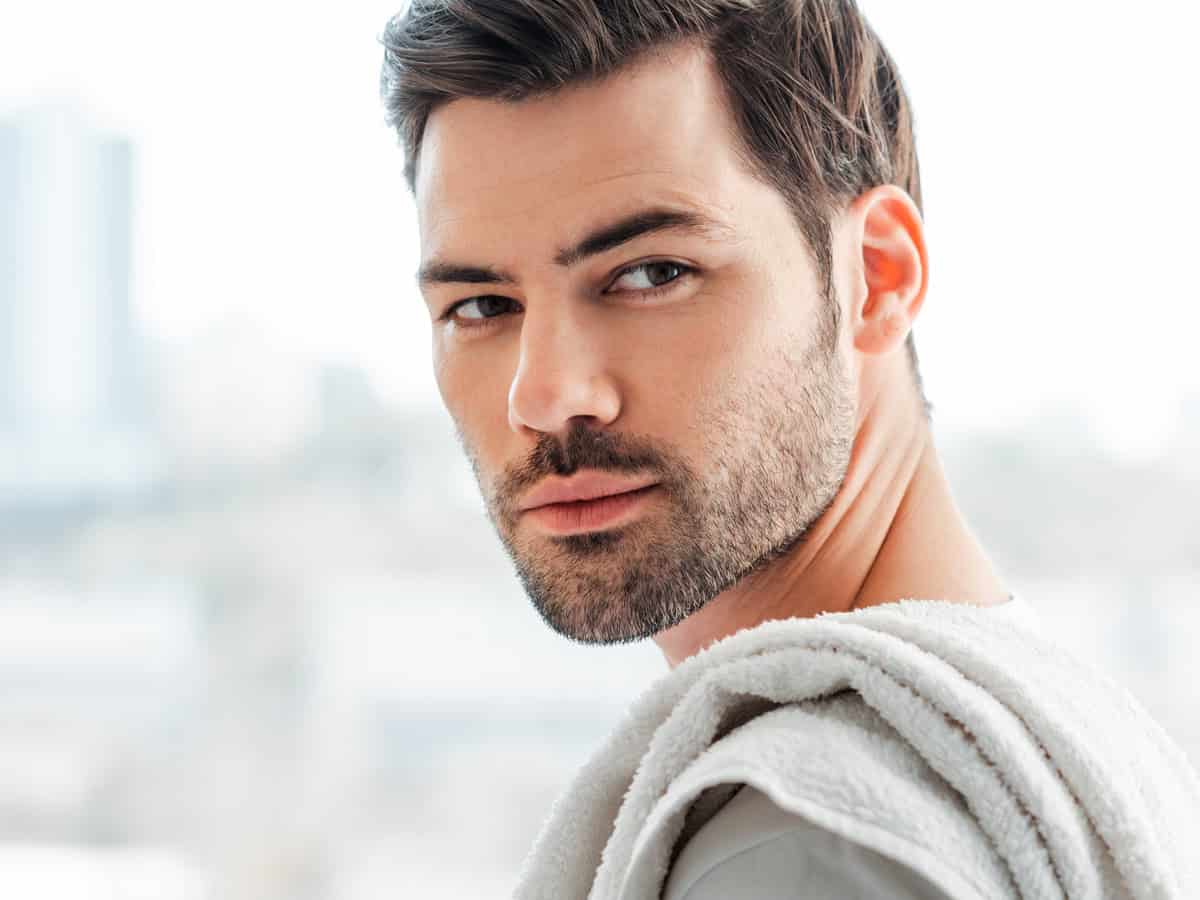 side view of handsome man with towel on shoulder looking away at home