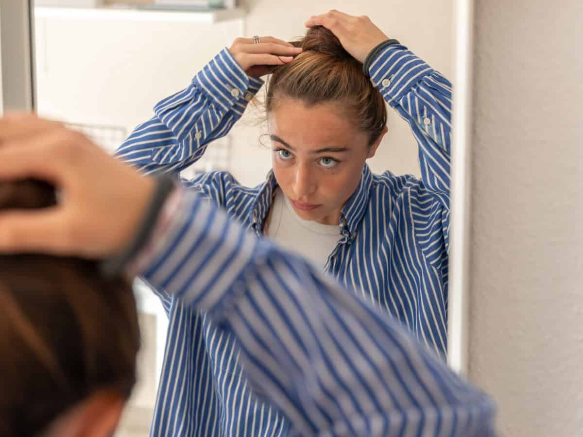 teenage girl doing her hair in front of the mirror. daily routine.