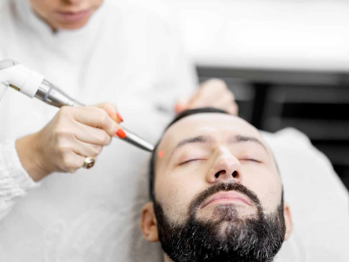 cosmetologist doing laser facelifting procedure in beauty clinic