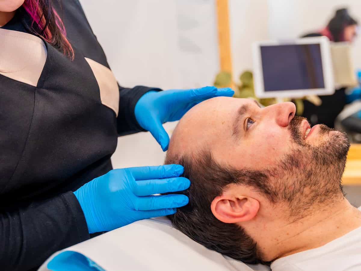 dermatologist inspecting the bald man's head before a hair treatment