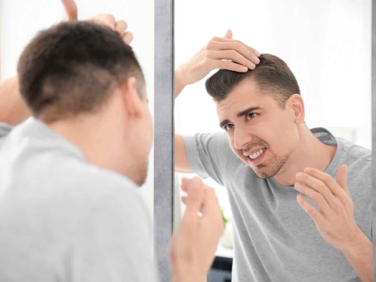 FUE vs DHI Hair Transplant - Which Method Wins for You young man with hair loss problem looking in mirror 2026 01 28 16 37 29 utc 1920x1280